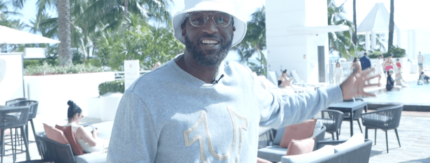 Man smiling and gesturing near poolside area.
